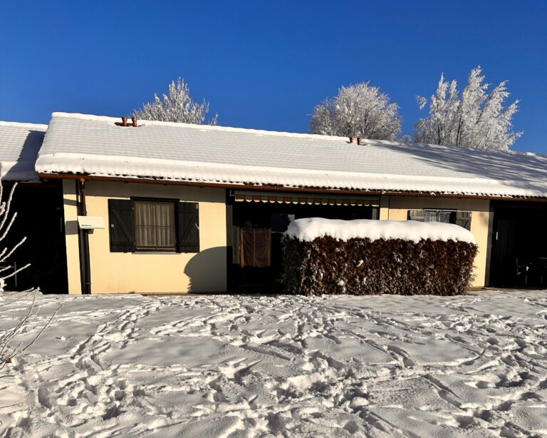 Ferienhaus im Winter mit verschneiter Hecke